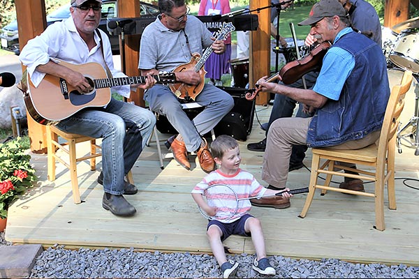 little boy pretending to play banjo on a badminton racquet