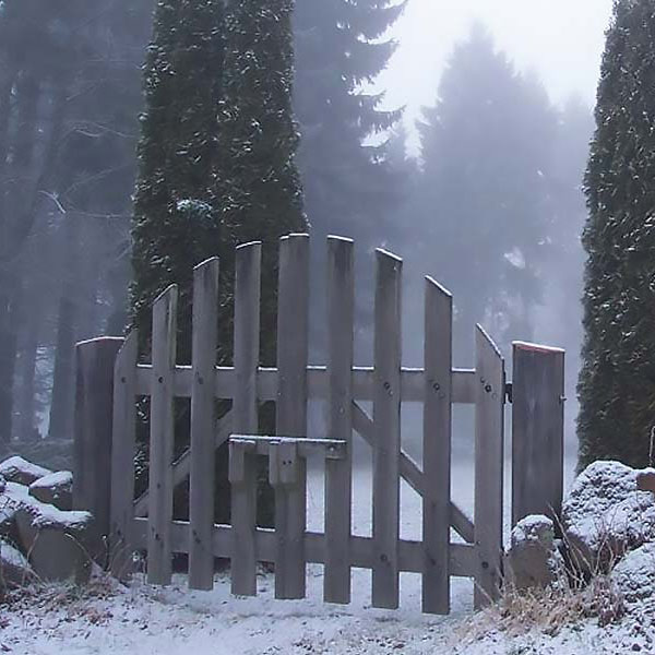 wooden gate in a stone wall around a cemetery