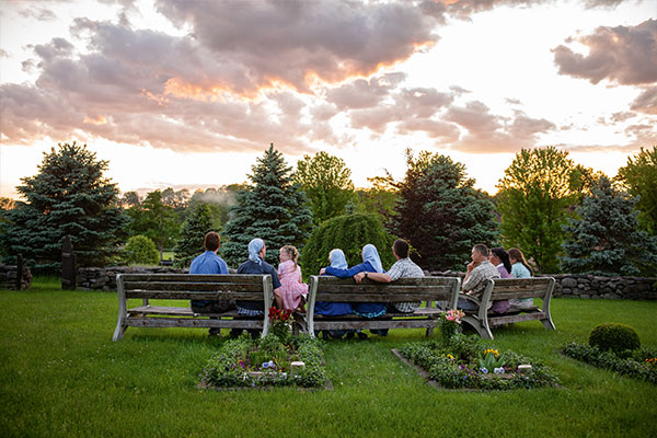 A widow and her family by a grave at sunset