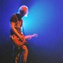 man playing a electric guitar backlit by spotlights