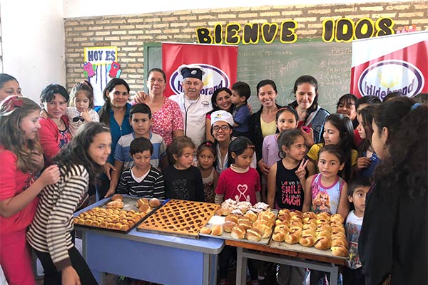 group of happy children standing around a table full of pastries