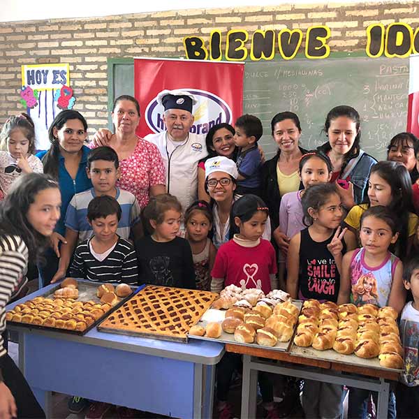 group of happy children standing around a table full of pastries