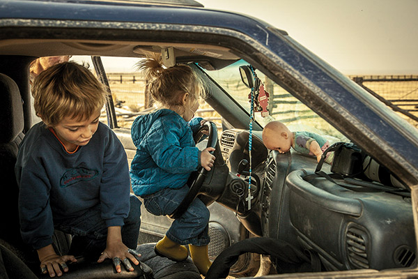 two kids playing in the front seat of an old car