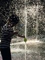 a boy playing in a fountain of water