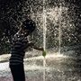 a boy playing in a fountain of water