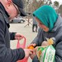 man giving bread and oranges to an older woman in a teal headscarf