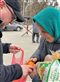 man giving bread and oranges to an older woman in a teal headscarf