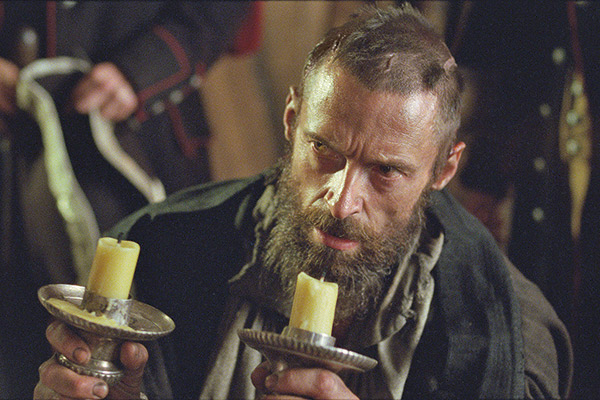 Hugh Jackman as Jean Valjean with two candlesticks