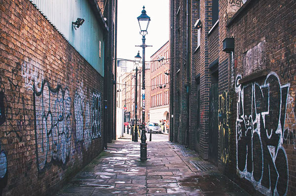 an empty street with graffiti on brick walls