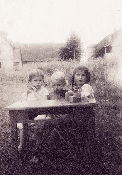 old photo of three children at a table outside