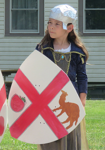 a young girl holding a homemade knight's sheild