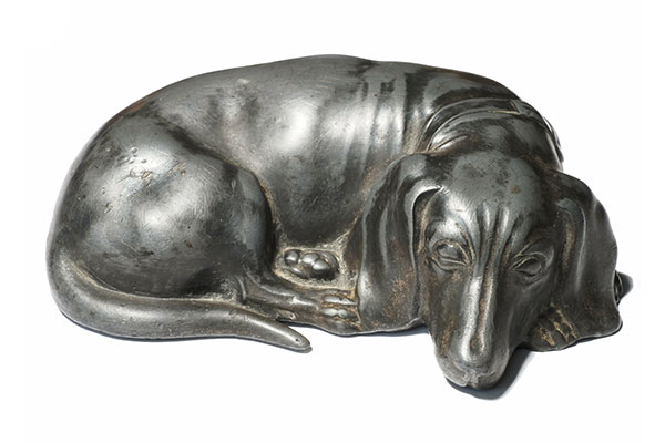 metal figurine of a dog lying down