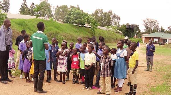 young men speaking to a group of children