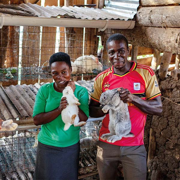 two people holding rabbits in a wooden shed
