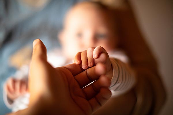 photo of a baby holding an adults hand