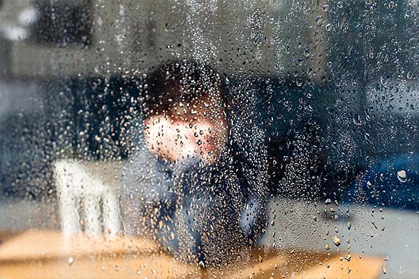 photo of a child looking through a rain covered window