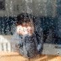 photo of a child looking through a rain covered window