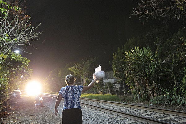a woman holding a bag of food next to a train track
