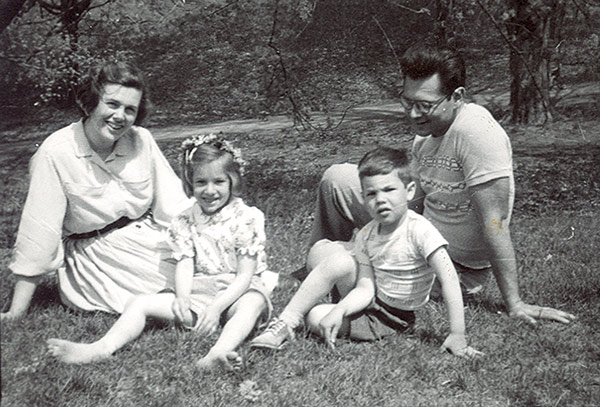 black and white photograph of a smiling couple and their children sitting on the grass