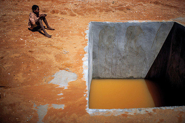 a boy sitting on red earth