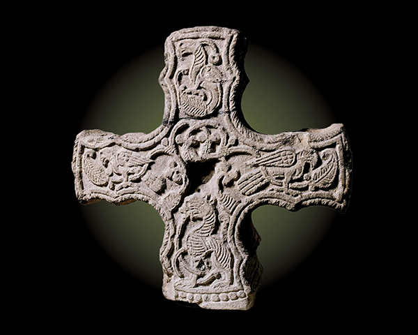 a carved stone cross on a black background