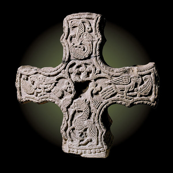 a carved stone cross on a black background