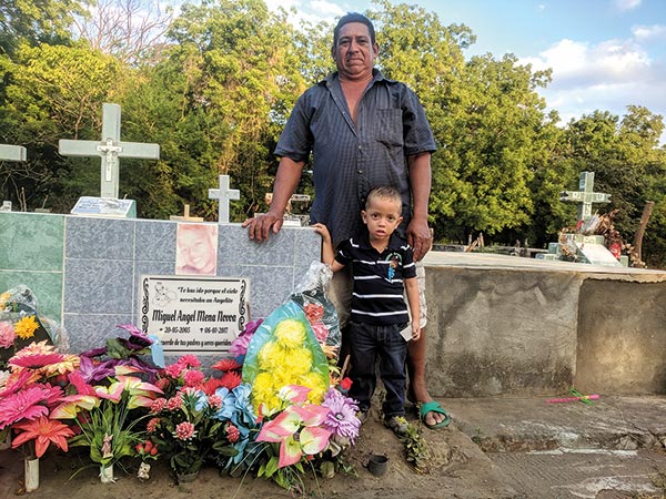 a man and a boy standing by a grave in a cemetary