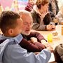 an elderly man sits with a young visitor to a community center