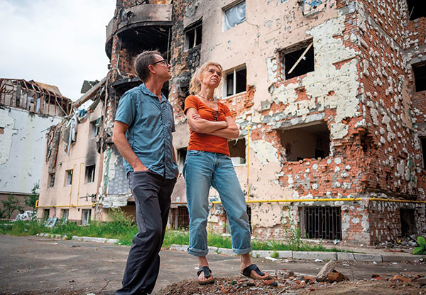 Steve and Oddny Gumaer by a bombed apartment building in Irpin, Ukraine