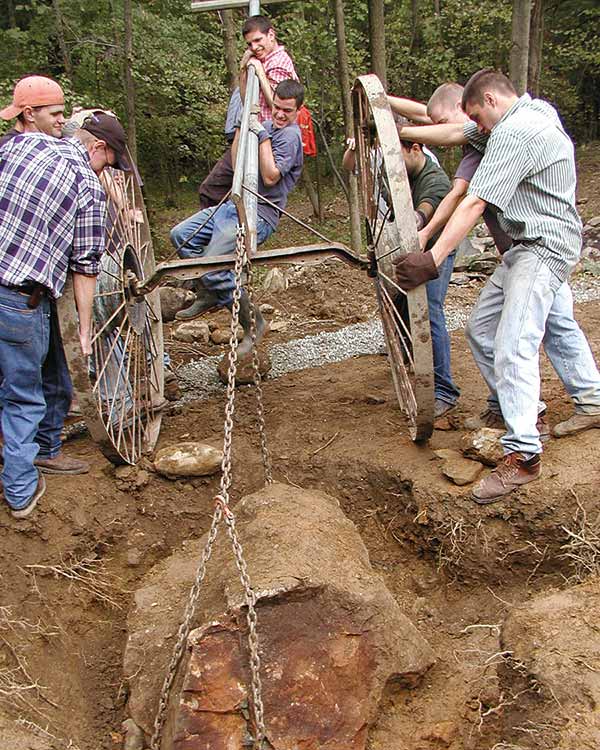 men pulling a huge stone out of a hole