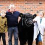 a few people posing for a photo with a cow