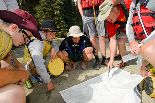 Boy Scouts and leader looking at a map on the ground