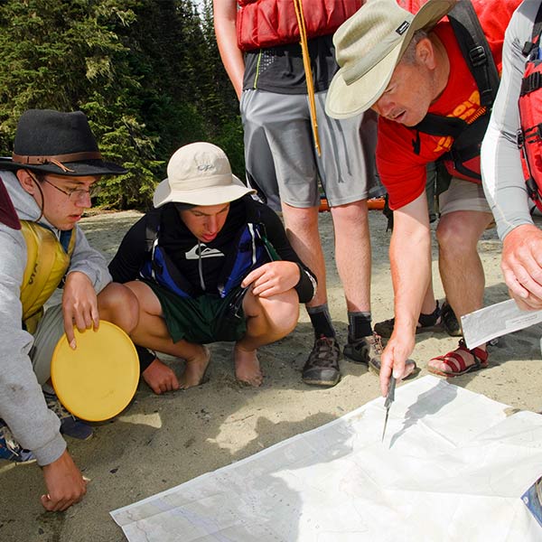 Boy Scouts and leader looking at a map on the ground