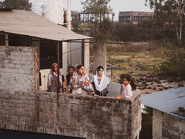 women standing by a stone wall