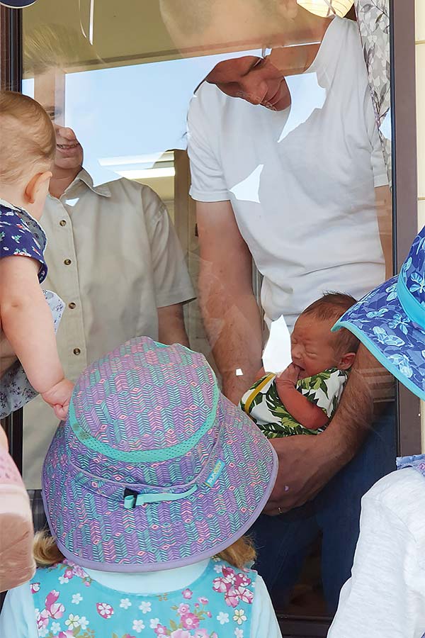 a couple showing their baby to children