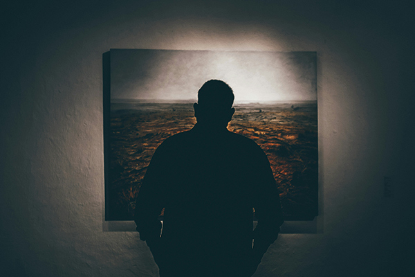 a man looking at a painting on a wall