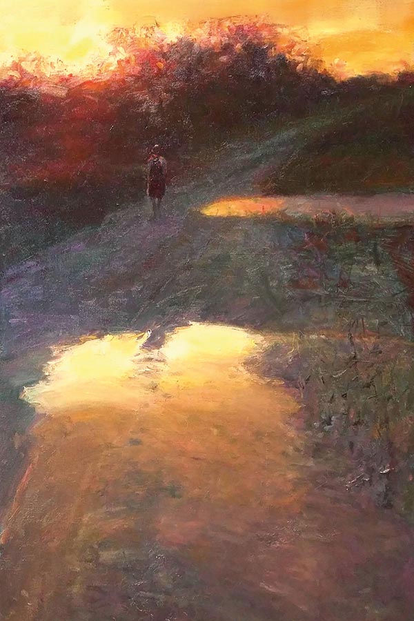 a person walking home on a dirt road at sunset