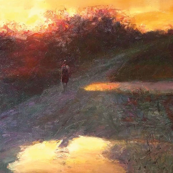 a person walking home on a dirt road at sunset