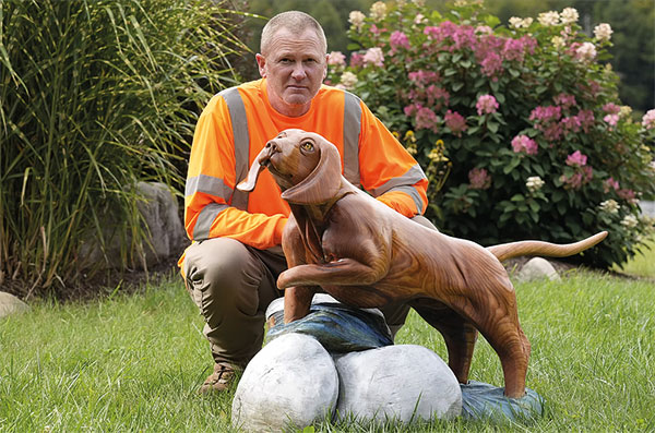 a sculpture artist posing by one of his creations