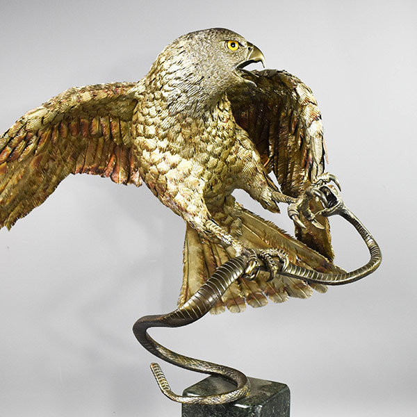 stainless steel sculpture of a hawk catching a snake