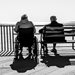 two old people sitting by the ocean